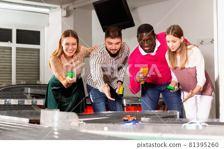 Portrait of smiling males and females posing with slot car racing game Portrait of smiling males and females posing with slot car racing game 81395260