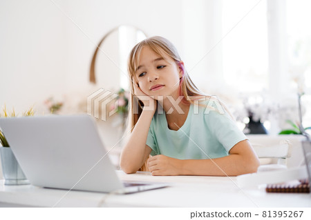 Happy little girl pupil using laptop at home 81395267
