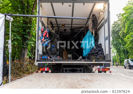Open cargo box of filming movie set production equipment transport truck van vehicle with many electrical cables wire, rack and sockets on city streey outdoors. Cinema or television supply rental car Open cargo box of filming movie set production equipment transport truck van vehicle with many electrical cables wire, rack and sockets on city streey outdoors. Cinema or television supply rental car 81397624