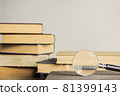 Open book and a magnifying glass over the light wall. 81399143