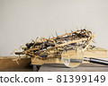 Open book, thorn crown and a magnifying glass over the light wall. 81399149