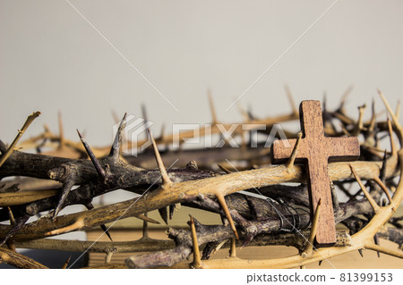 A wooden cross with thorn crown on a wooden table. A wooden cross with thorn crown on a wooden table. 81399153
