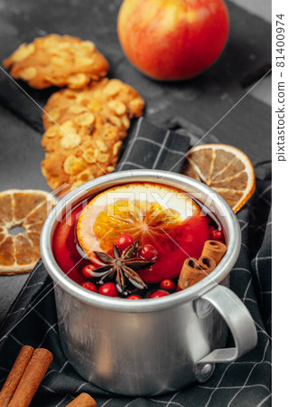 Close up of mulled wine cup with spices and berries on grey table Close up of mulled wine cup with spices and berries on grey table 81400974