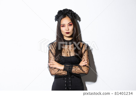 Skeptical and unamused asian woman dressed in halloween costume looking disappointed at camera, cross arms chest. Female in black gothic dress and wreath judging someone Skeptical and unamused asian woman dressed in halloween costume looking disappointed at camera, cross arms chest. Female in black gothic dress and wreath judging someone 81401234