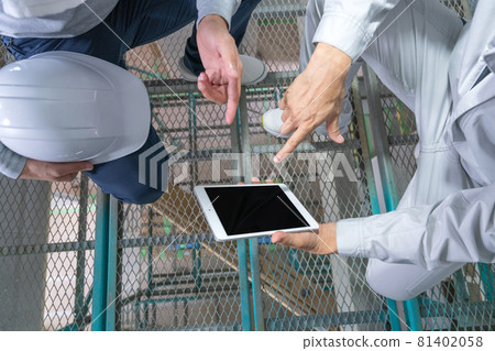 在獨戶建築工地二樓的腳手架上看著平板電腦的兩個男人的手 81402058