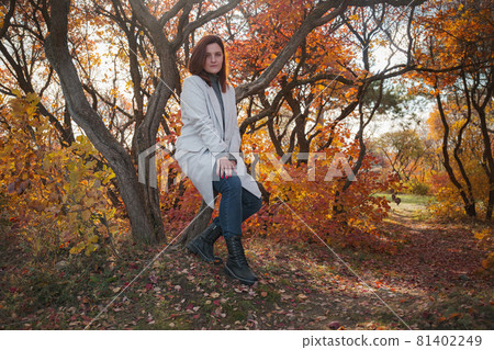 A cute redheaded woman in good spirits poses on an autumn day A cute redheaded woman in good spirits poses on an autumn day 81402249