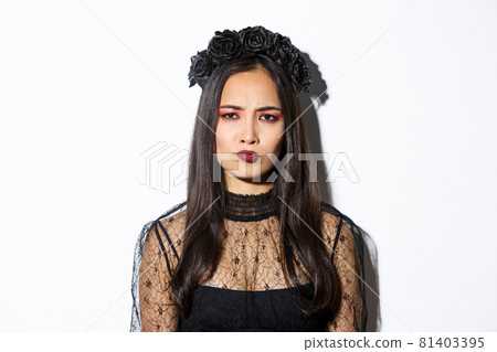 Close-up of disappointed grimacing girl in witch costume looking displeased, frowning upset, standing over white background Close-up of disappointed grimacing girl in witch costume looking displeased, frowning upset, standing over white background 81403395