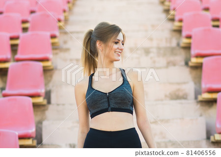 A female coach with dark hair stands on the red running track of the stadium A female coach with dark hair stands on the red running track of the stadium 81406556