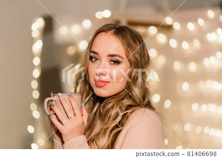 Happy young lady with long hair near the fireplace and the Christmas tree, gifts. New year concept. Happy young lady with long hair near the fireplace and the Christmas tree, gifts. New year concept. 81406698