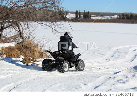 Child Driving His Quad Onto a Frozen Lake 81406718