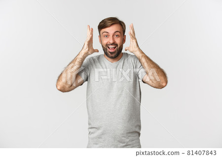 Image of excited happy guy hearing amazing news, standing over white background and smiling Image of excited happy guy hearing amazing news, standing over white background and smiling 81407843