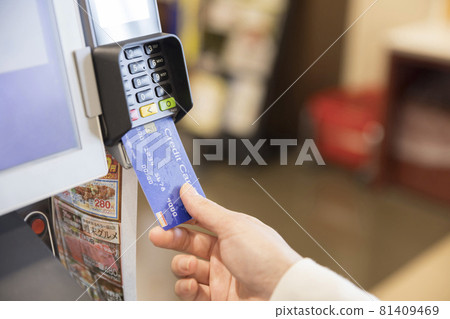 A woman who inserts a credit card at a supermarket's automatic checkout machine A woman who inserts a credit card at a supermarket's automatic checkout machine 81409469