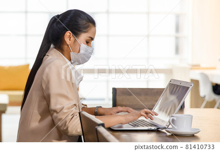 covid-19 prevention and social distancing in the company. Asian female office worker wearing a facemask and sitting alone in the office. Coronavirus protection concept covid-19 prevention and social distancing in the company. Asian female office worker wearing a facemask and sitting alone in the office. Coronavirus protection concept 81410733