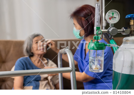 Elderly woman wearing oxygen nasal cannula at home. 81410804