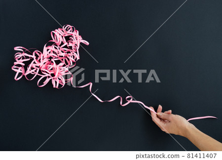 Female hand holding pink curly ribbon heart. Serpentine heart. Female hand holding pink curly ribbon heart. Serpentine heart. 81411407