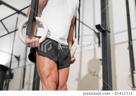 Young Male Athlete exercising With Gymnastic Rings In The Gym.  81411515