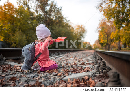 adorable toddler girl playing with a scoop on the rails. dangerous games of children adorable toddler girl playing with a scoop on the rails. dangerous games of children 81411551