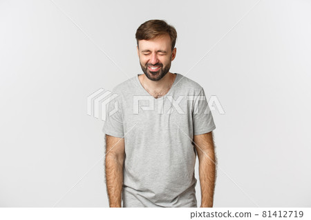 Image of cheerful bearded guy in gray t-shirt, laughing and having fun, standing over white background 81412719
