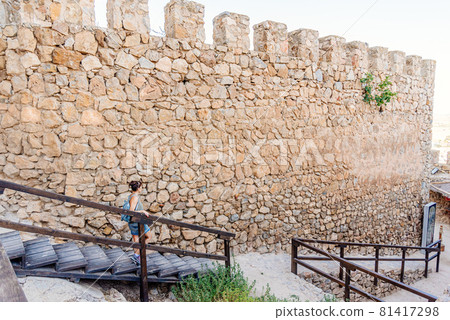 Woman visiting the wall of a restored medieval castle Woman visiting the wall of a restored medieval castle 81417298