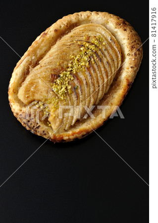 Bird's-eye view of pistachio and sliced apple tartlets on a black background Bird's-eye view of pistachio and sliced apple tartlets on a black background 81417916