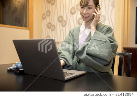 A young woman in a yukata working at a hot spring inn 81418094