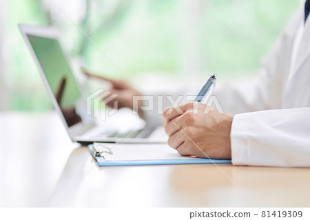 A male doctor who looks up on a computer and takes notes 81419309