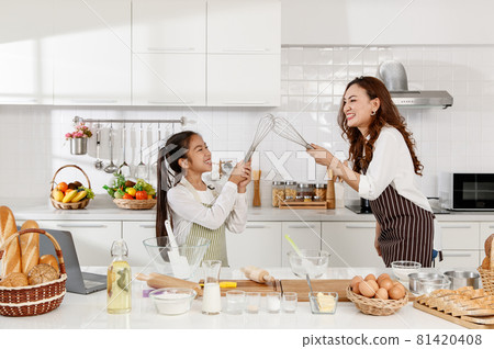 Asian mother holding a rolling pin and daughter were playing happily while make cake in the modern kitchen at home. concept of love and bond. Asian mother holding a rolling pin and daughter were playing happily while make cake in the modern kitchen at home. concept of love and bond. 81420408