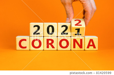 Symbol of covid-19 pandemic in 2022. Doctor turns a wooden cube and changes words 'corona 2021' to 'corona 2022'. Beautiful orange background, copy space. Medical, covid-19 pandemic in 2022 concept. 81420599