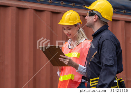 Industrial worker works with co-worker at overseas shipping container yard 81421516