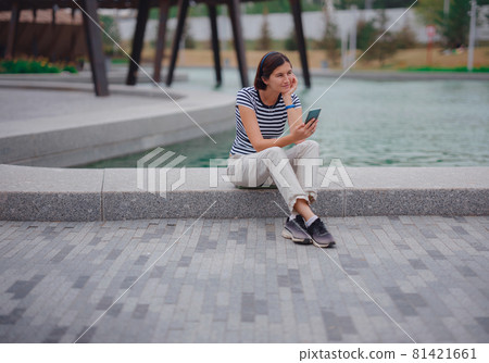 Portrait of young woman in park with smartphone Portrait of young woman in park with smartphone 81421661