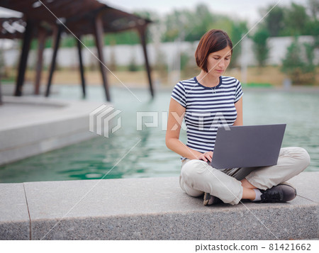female student working with laptop in campus park. female student working with laptop in campus park. 81421662