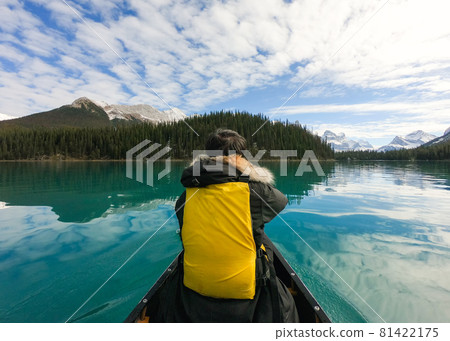 Traveler man canoeing into Spirit island on Maligne lake with Canadian Rockies on sunny day 81422175