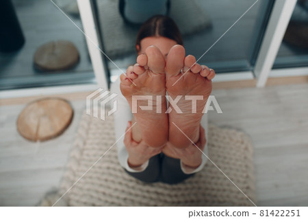 Adult mature woman doing yoga at home living room with online tutorials on laptop 81422251