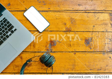 Flat lay of laptop, wireless headphones and mobile phone on wooden table. 81423163