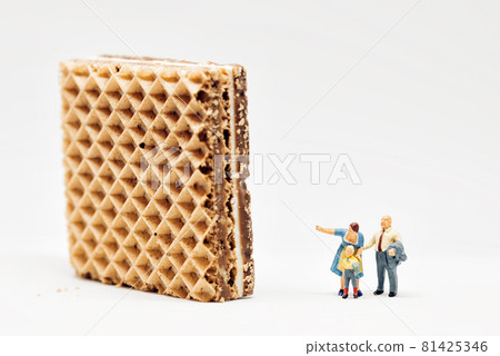 Miniature people. Two adults showing giant waffle to a boy Miniature people. Two adults showing giant waffle to a boy 81425346