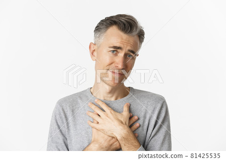 Close-up of thankful middle-aged man, holding hands on heart and feeling touched, appreciate kind gesture, standing over white background Close-up of thankful middle-aged man, holding hands on heart and feeling touched, appreciate kind gesture, standing over white background 81425535