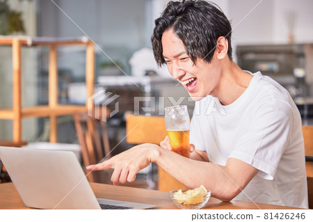 A young man having a fun conversation at an online drinking party A young man having a fun conversation at an online drinking party 81426246