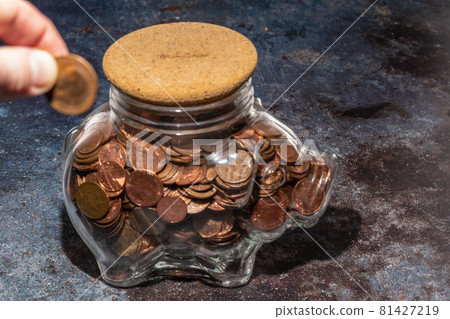 Large glass piggy bank full of copper coins Large glass piggy bank full of copper coins 81427219