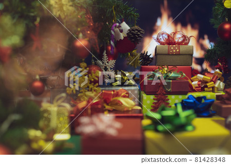 Pile of shiny luxury colorful gift boxes. Christmas and new year celebrate gifts stack beside full decorated Xmas tree with flame of fire in fireplace blur in background to give for family members Pile of shiny luxury colorful gift boxes. Christmas and new year celebrate gifts stack beside full decorated Xmas tree with flame of fire in fireplace blur in background to give for family members 81428348