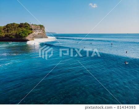 Long surfing waves in blue ocean and cliff at background. Aerial view of tropical island with waves 81434393