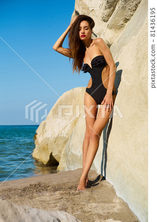 Beautiful elegant lady poses on the beach in black swimming suit Beautiful elegant lady poses on the beach in black swimming suit 81436195