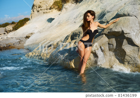 Beautiful elegant lady poses on the beach in black swimming suit Beautiful elegant lady poses on the beach in black swimming suit 81436199