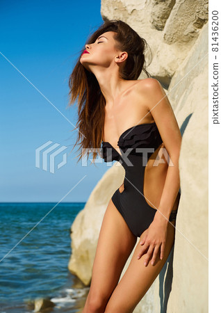 Beautiful elegant lady poses on the beach in black swimming suit Beautiful elegant lady poses on the beach in black swimming suit 81436200