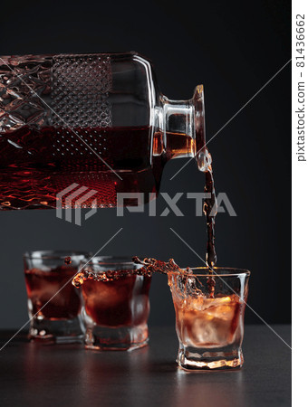 Whiskey pours into a frosted glass with natural ice. 81436662