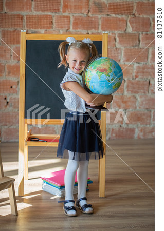 Portrait of schoolgirl standing in front of chalkboard with globe in her hands Portrait of schoolgirl standing in front of chalkboard with globe in her hands 81437810