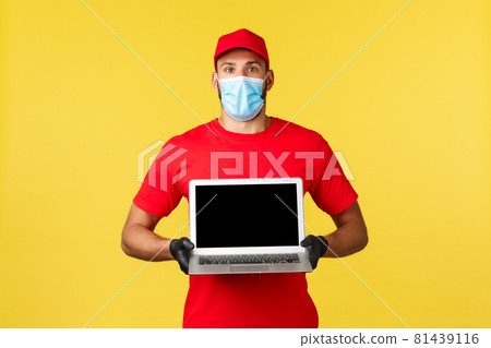 covid-19, safe shopping, express delivery and order tracking concept. Surprised and impressed courier in red uniform and medical mask showing awesome advertisement on laptop screen covid-19, safe shopping, express delivery and order tracking concept. Surprised and impressed courier in red uniform and medical mask showing awesome advertisement on laptop screen 81439116