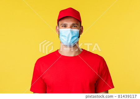 Covid-19, delivery orders, shopping, contactless payment and social distancing concept. Pleasant young nice male employee in red uniform cap and t-shirt, pleased help customer, wear medical mask 81439117