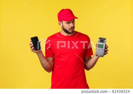 Contactless payment, online delivery, internet shopping concept. Confused young courier in red uniform, newbie courier figure out how POS terminal works, holding mobile phone Contactless payment, online delivery, internet shopping concept. Confused young courier in red uniform, newbie courier figure out how POS terminal works, holding mobile phone 81439324
