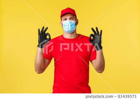 Express delivery during pandemic, covid-19, safe shipping, online shopping concept. Determined logistics company employee, courier in red uniform provide quality transportation of parcels to clients 81439371