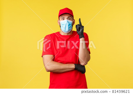 Express delivery during pandemic, covid-19, safe shipping, online shopping concept. Excited courier in medical mask and uniform, gloves raise index finger, have plan or suggestion, think-up solution Express delivery during pandemic, covid-19, safe shipping, online shopping concept. Excited courier in medical mask and uniform, gloves raise index finger, have plan or suggestion, think-up solution 81439621